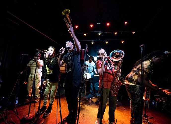 Members of the Rebirth Brass Band performing energetically on stage, captivating the audience with their signature New Orleans brass sound