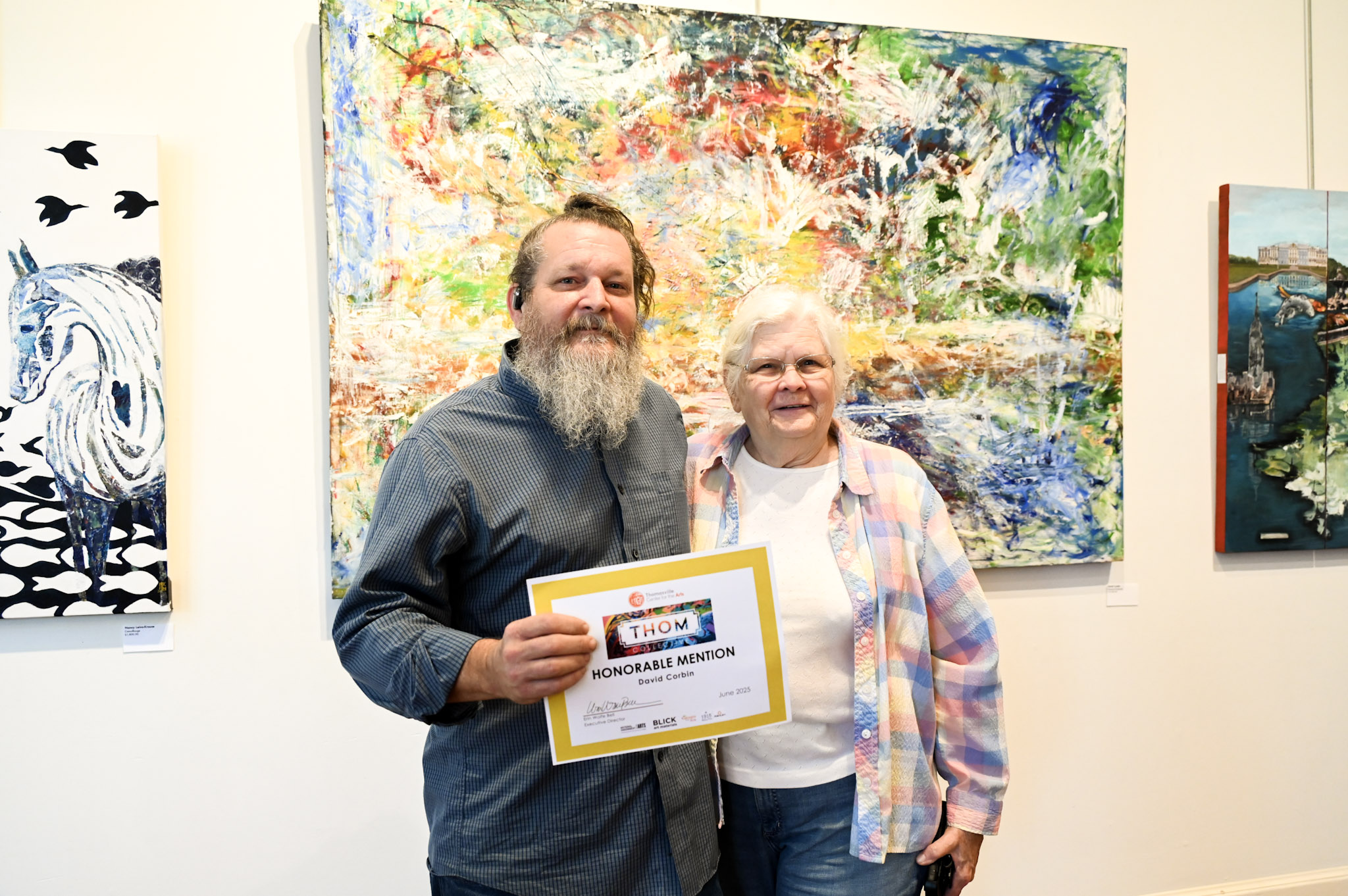 Pictured is an artist facing a canvas, painting an illustration of a golden retriever.